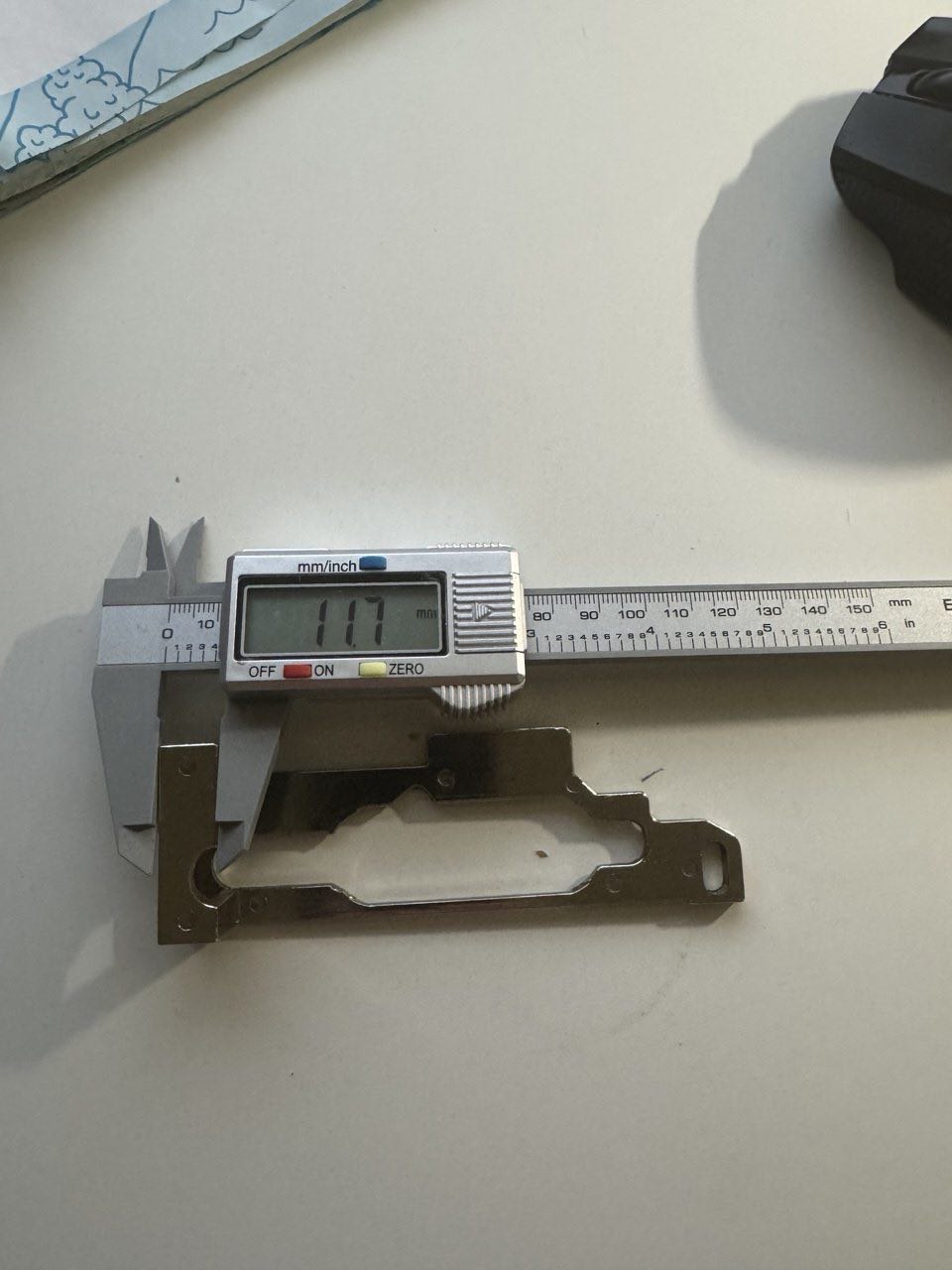 CNC metal part measured with digital caliper at 11.7 mm